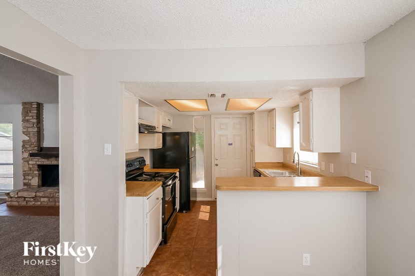 a kitchen with white cabinets and a black refrigerator