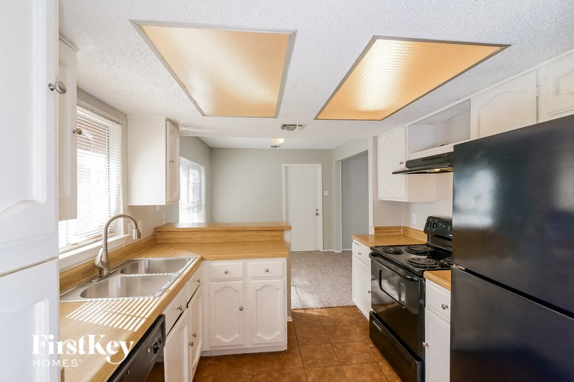 a kitchen with white cabinets and black appliances