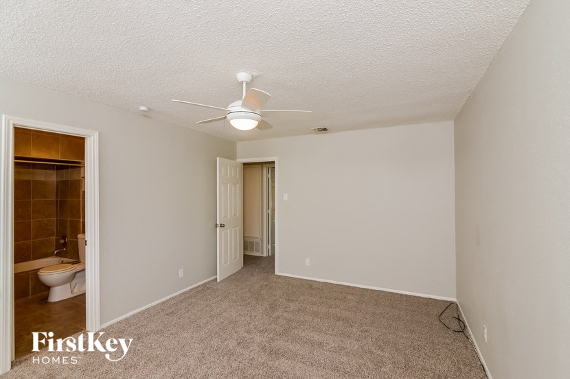 an empty living room with a ceiling fan and a bathroom