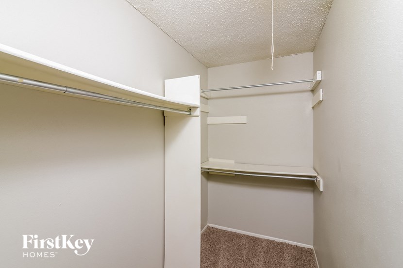 a walk in closet in a white room with a mirrored closet door