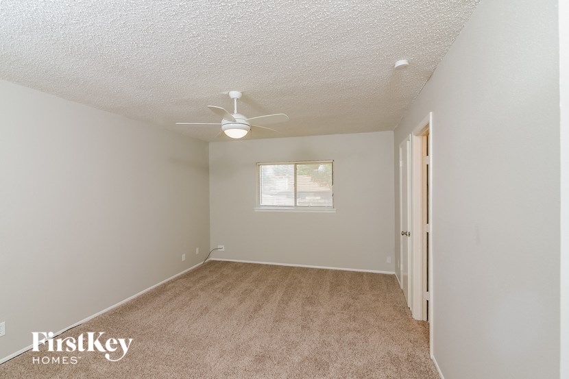 an empty room with a ceiling fan and a window