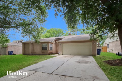 A house with a driveway and a tree in front of it.