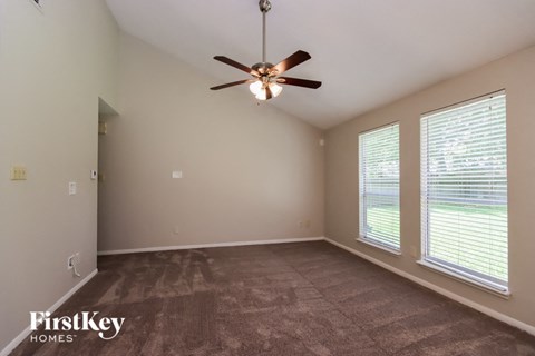 A room with a ceiling fan and carpeted floor.