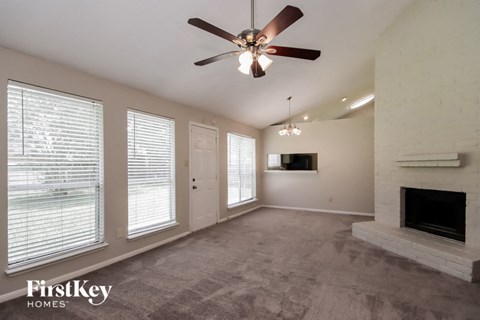 A spacious living room with a fireplace and a ceiling fan.