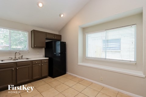A kitchen with brown cabinets and a black refrigerator.