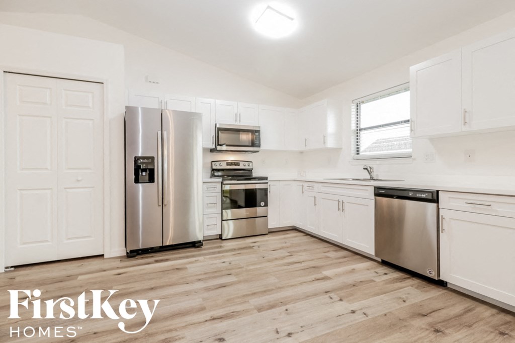 a white kitchen with stainless steel appliances and white cabinets