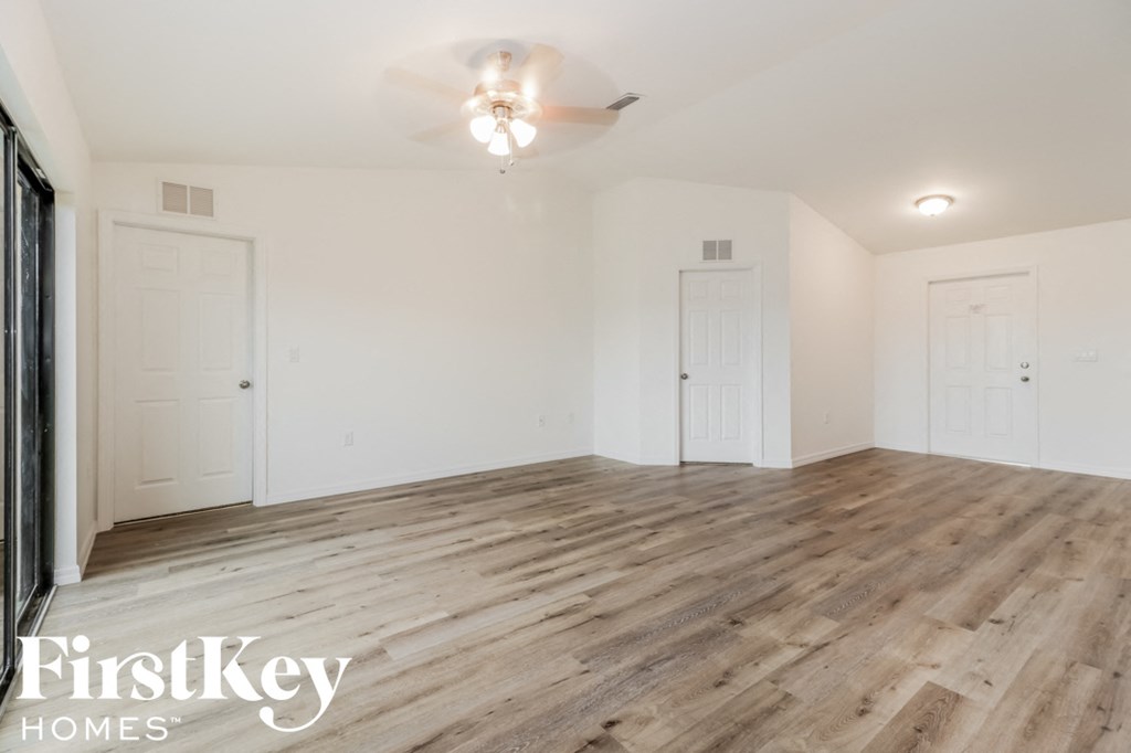an empty living room with wood flooring and white walls