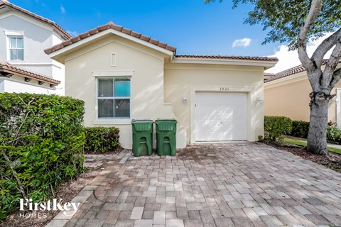 a home with a garage and a driveway with two green trash cans