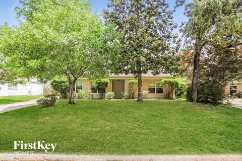 A house with a lawn and trees in front of it.