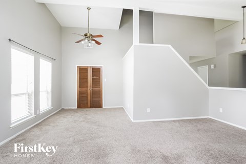 A spacious room with a ceiling fan and a door.