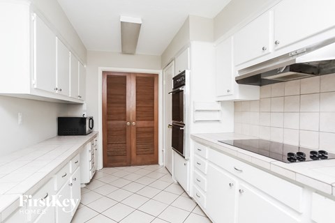 A kitchen with white cabinets and a black microwave.