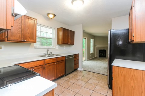 A kitchen with wooden cabinets and a black refrigerator.