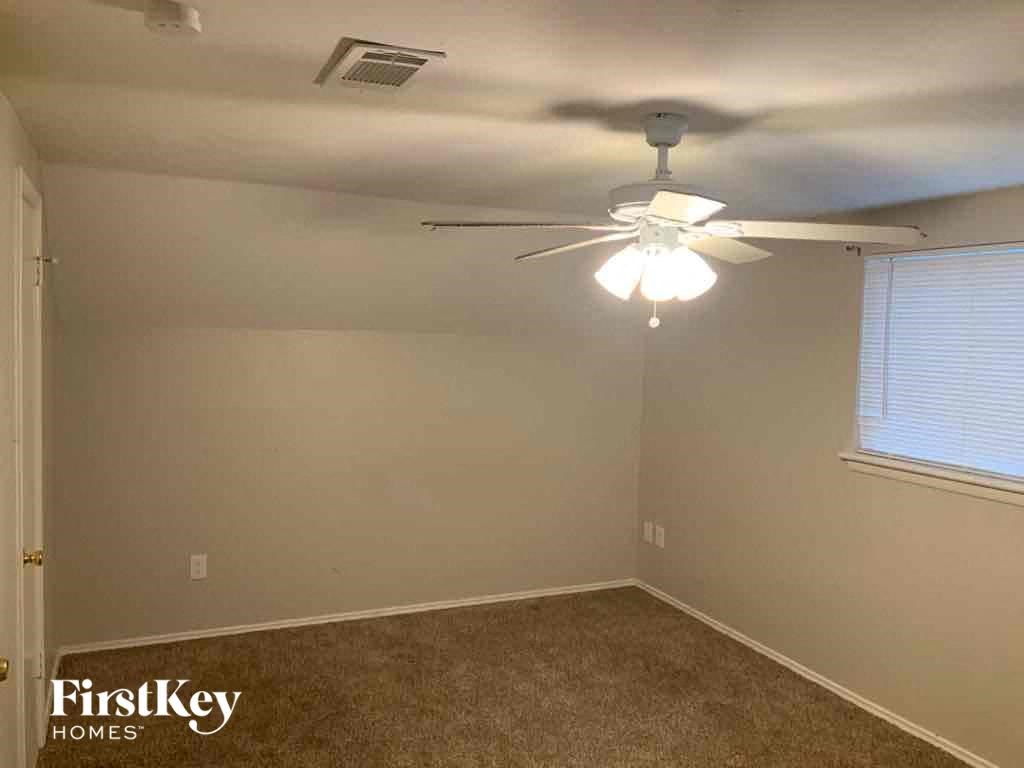 A room with a fan and carpeted floor.
