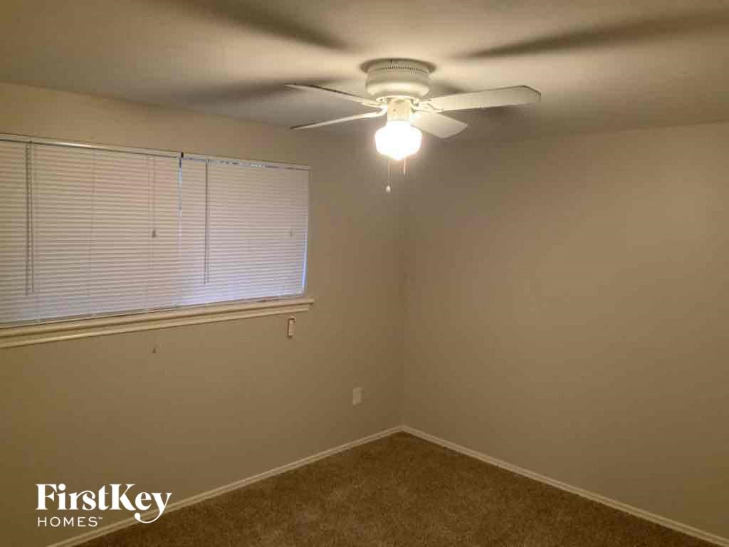 A room with a ceiling fan and a window with blinds.
