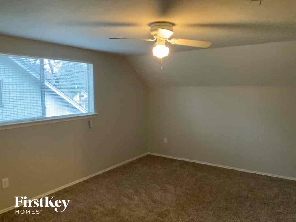 A room with a carpeted floor and a ceiling fan.
