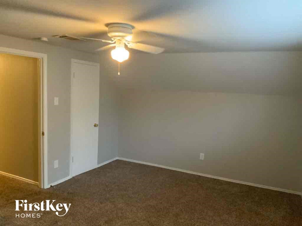 A room with a ceiling fan and a light bulb hanging from it.