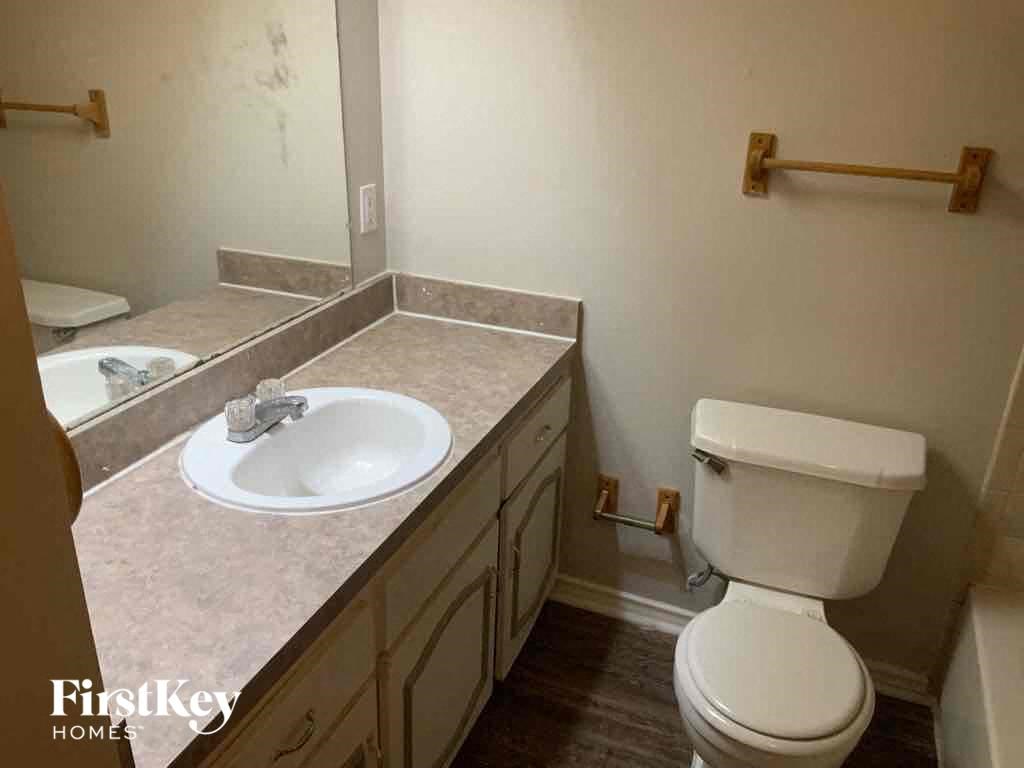 A bathroom with a toilet, sink, and mirror.