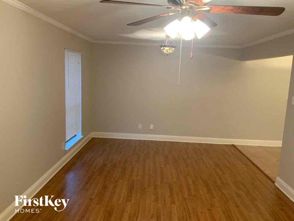 A room with a ceiling fan and wooden flooring.