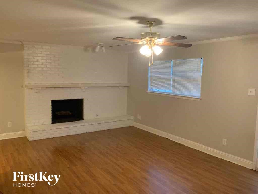 A living room with a fireplace and a ceiling fan.