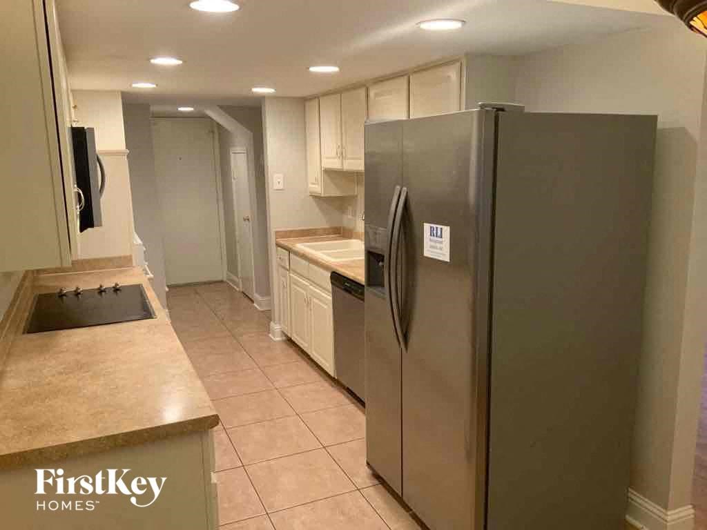 A kitchen with a refrigerator, sink, and cabinets.