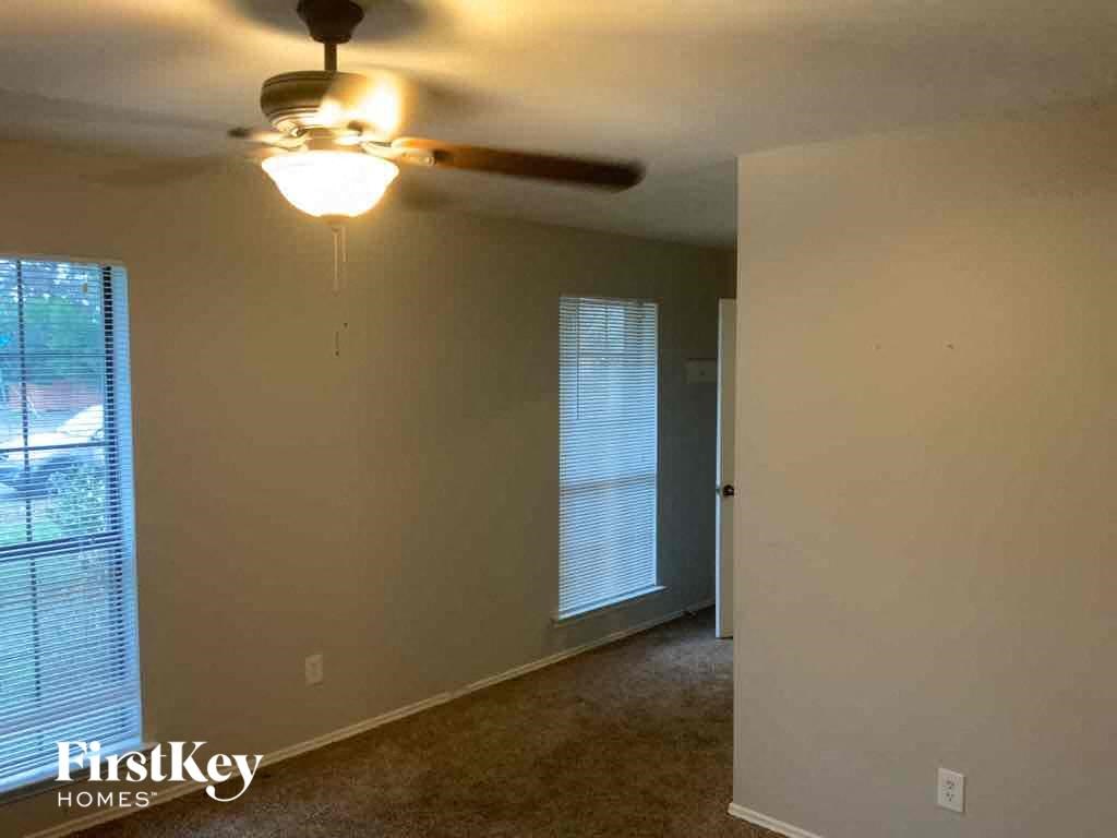 A room with a ceiling fan and a window with blinds.
