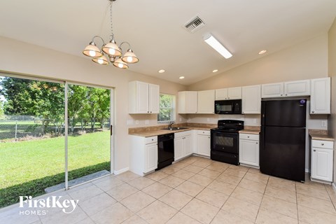 A kitchen with black appliances and white cabinets.