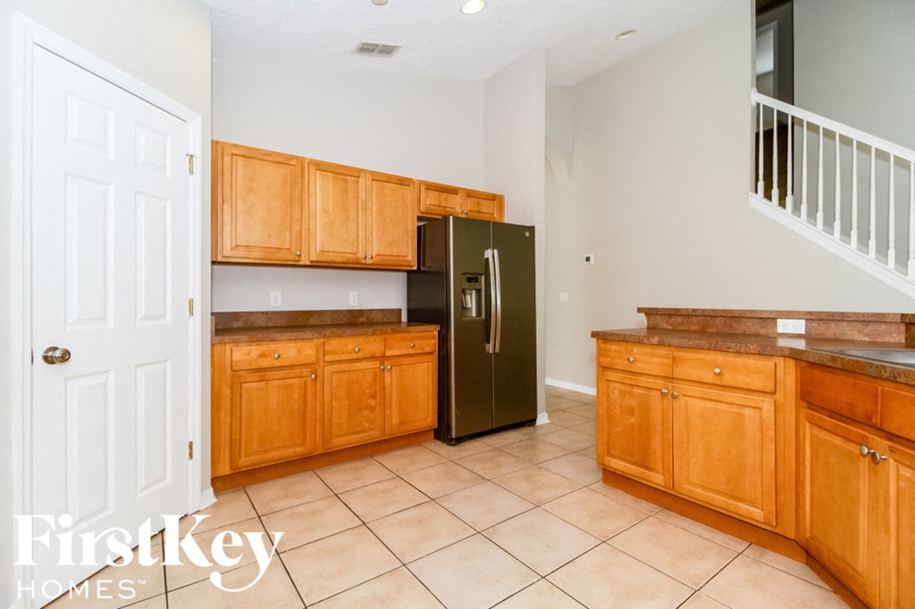 A kitchen with wooden cabinets and a black refrigerator.