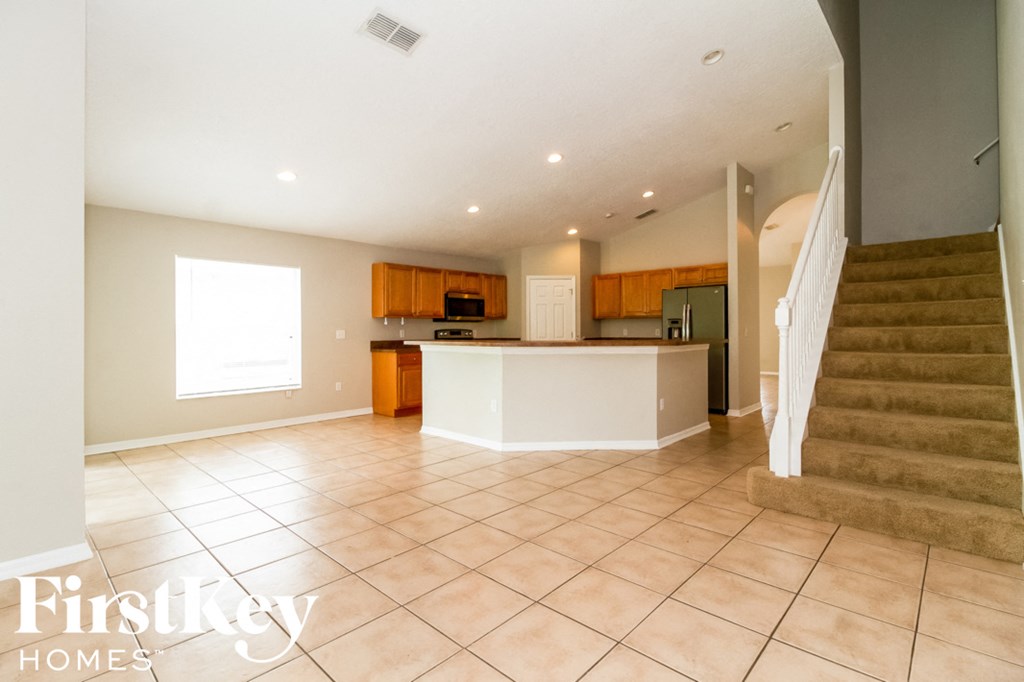 A spacious living room with a staircase leading to the upper floor.