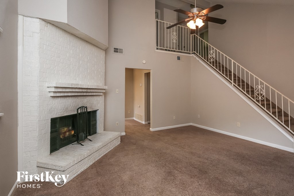 an empty living room with a fireplace and a ceiling fan