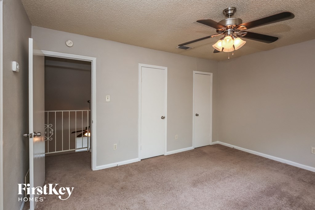 a bedroom with a ceiling fan and a door to a closet