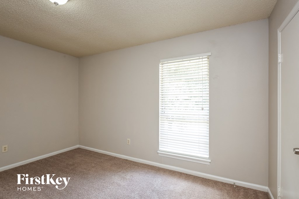 a bedroom with a large window and a carpeted floor