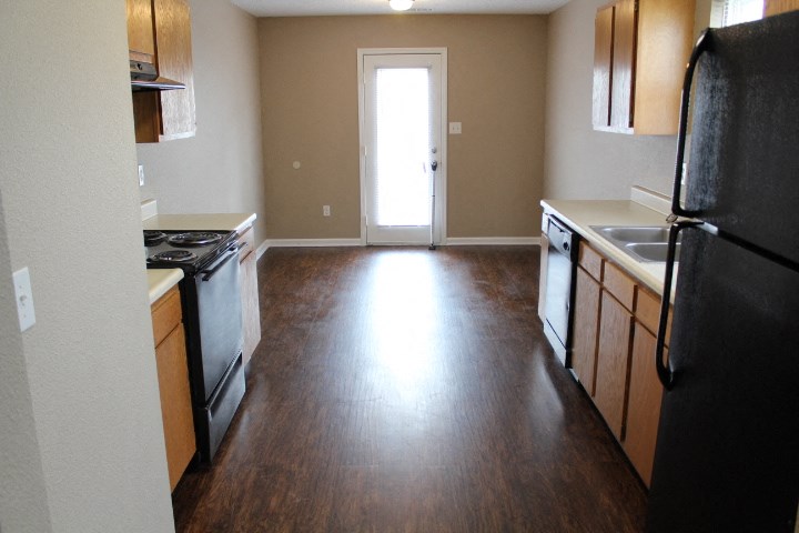 an empty kitchen with wood flooring and black appliances
