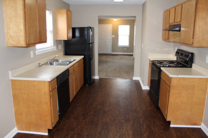 an empty kitchen with wooden cabinets and a black refrigerator