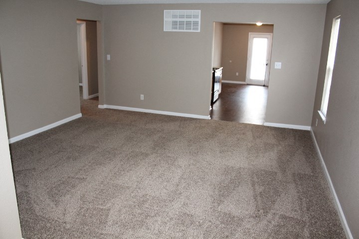 an empty living room with a carpeted floor