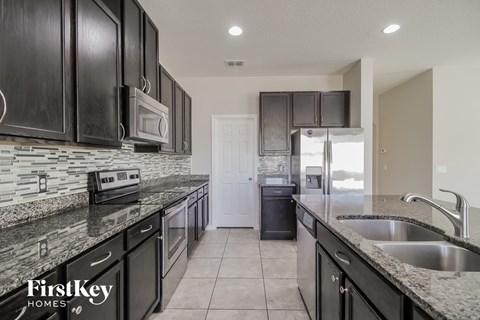 A kitchen with black cabinets and a granite countertop.