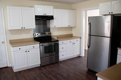 A kitchen with white cabinets and a stainless steel refrigerator.