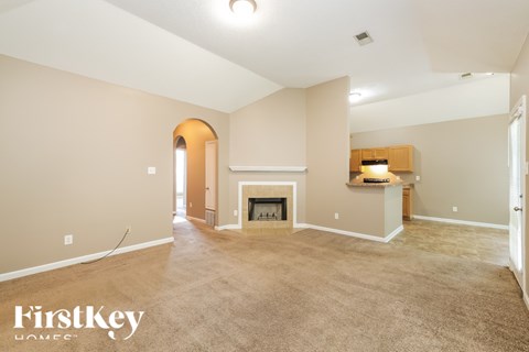 A spacious living room with a fireplace and a carpeted floor.