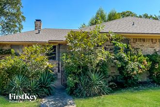 the front of a brick house with a pathway and plants
