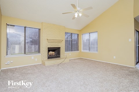 A spacious room with a fireplace and a ceiling fan.