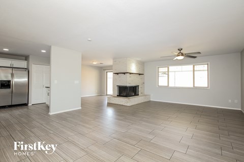 A spacious living room with a fireplace and a ceiling fan.