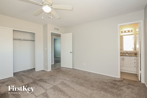A spacious room with a carpeted floor and a ceiling fan.