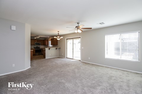 A spacious living room with a ceiling fan and a large window.