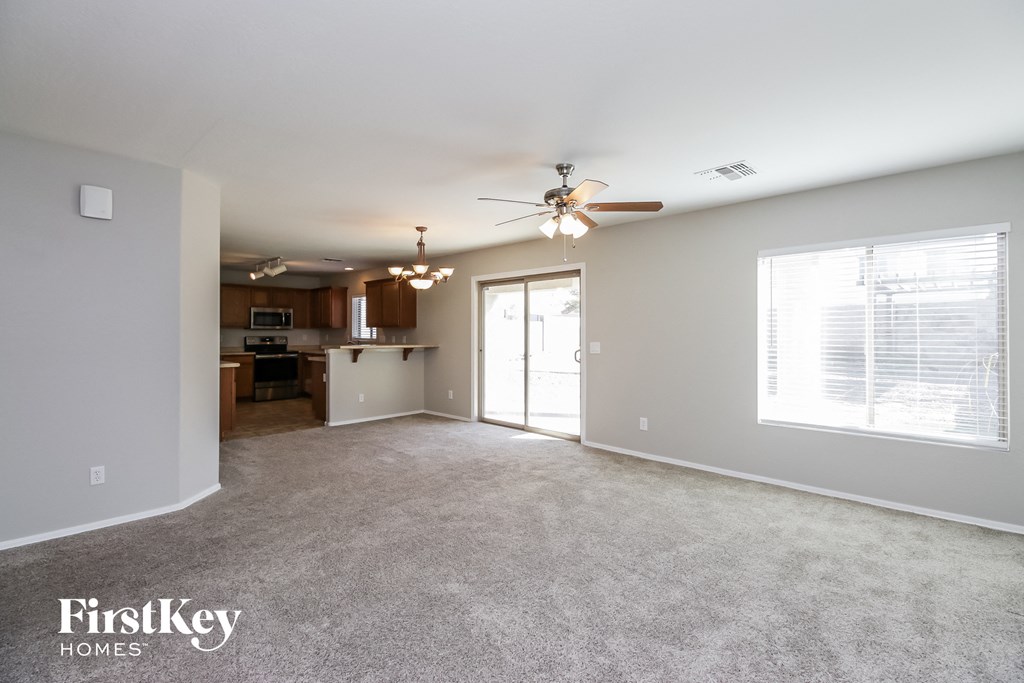 A spacious living room with a ceiling fan and a large window.