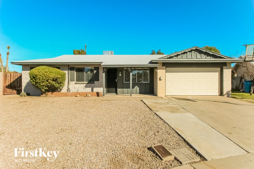A house with a grey roof and a garage door is for sale.