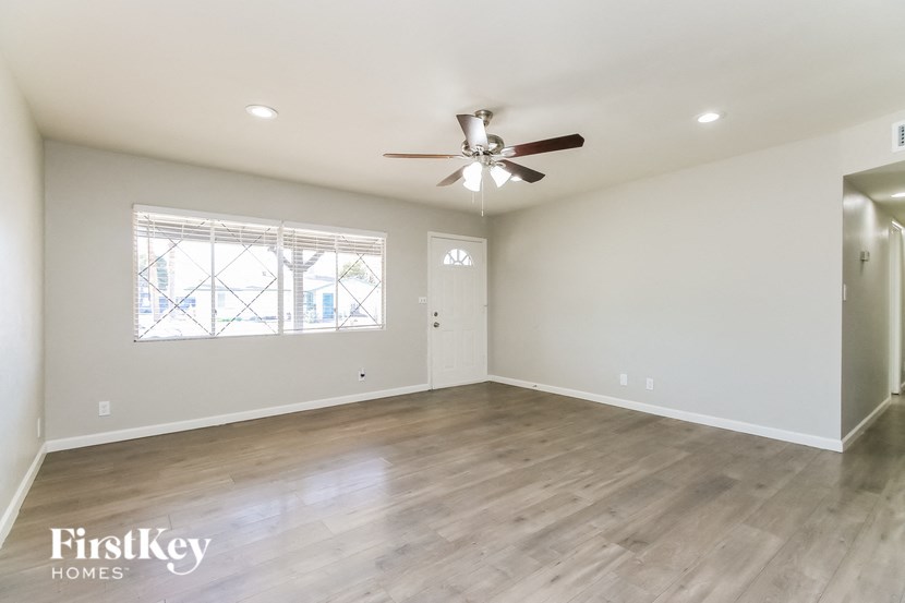 A spacious room with a ceiling fan and a window with blinds.