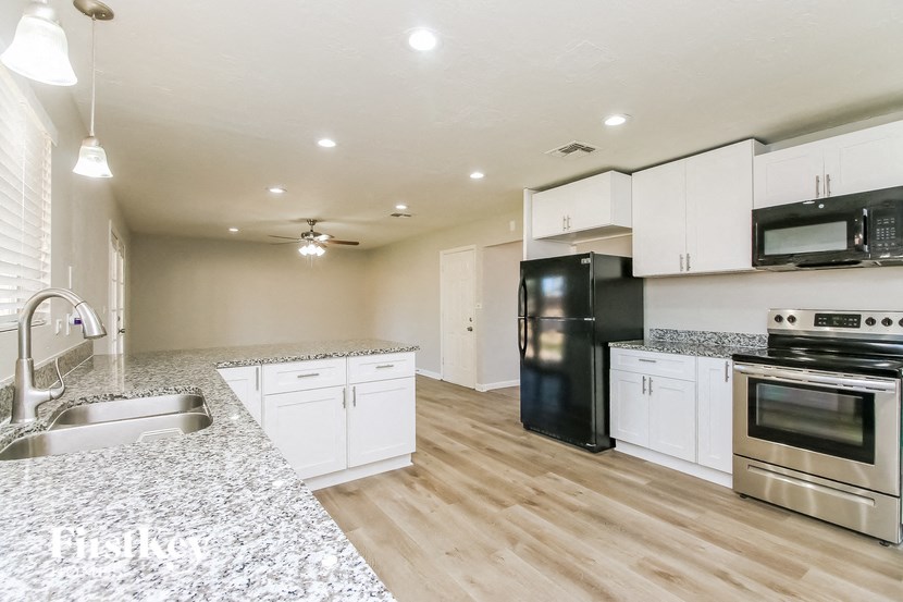 A kitchen with black appliances and white cabinets.