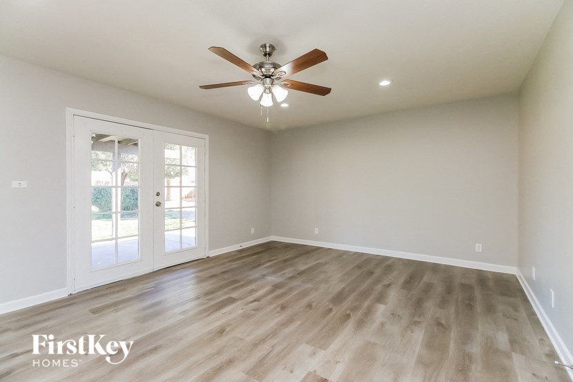A room with a ceiling fan and wooden flooring.