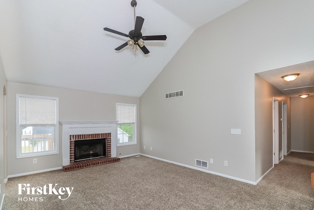 the living room has a fireplace and a ceiling fan