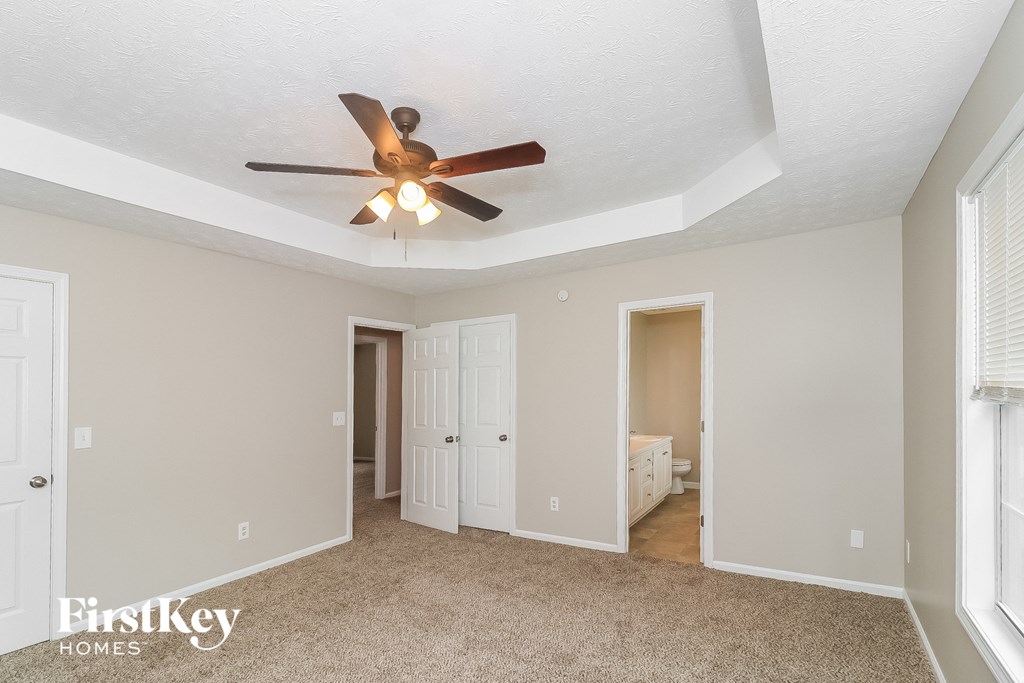 a living room with a ceiling fan and a door to a closet