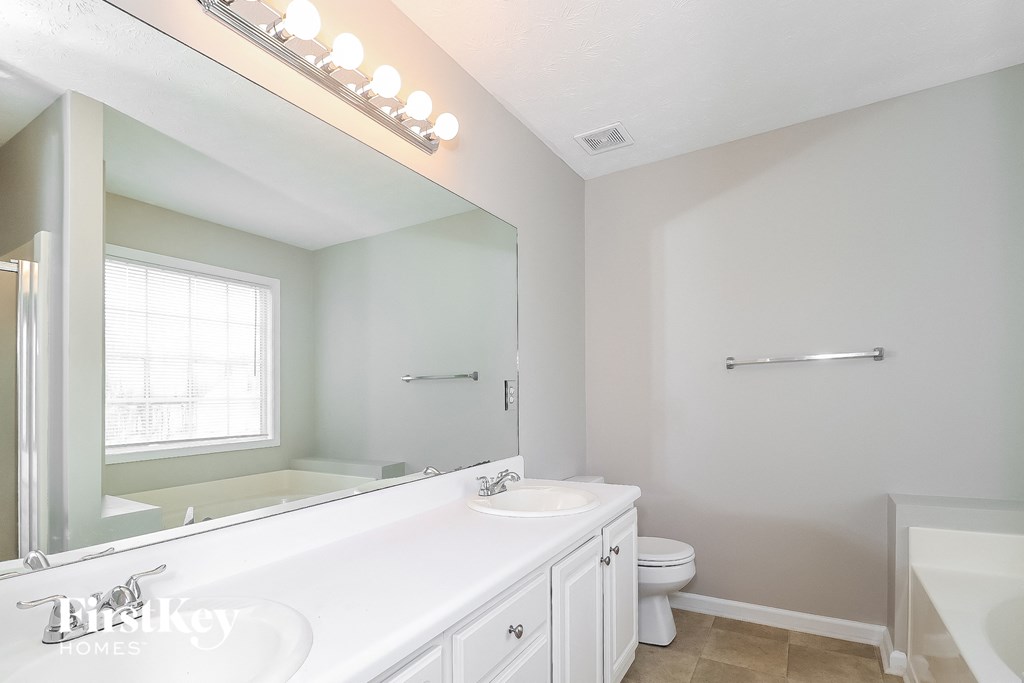 a bathroom with a large mirror and a sink and a toilet